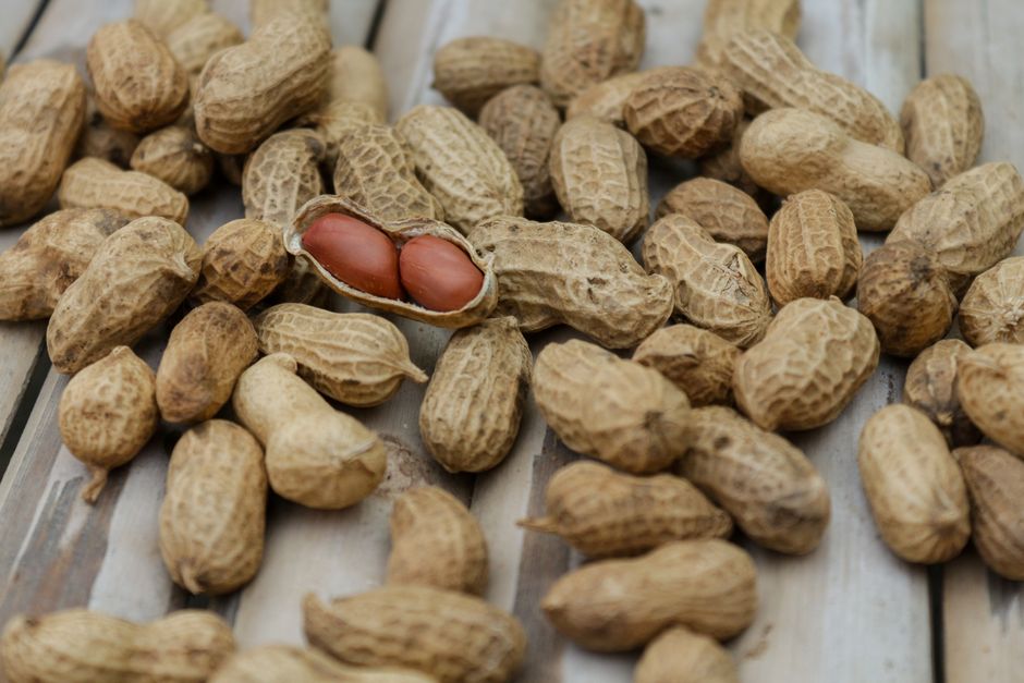 A detailed close-up of peanuts in their shells scattered on a wooden surface.