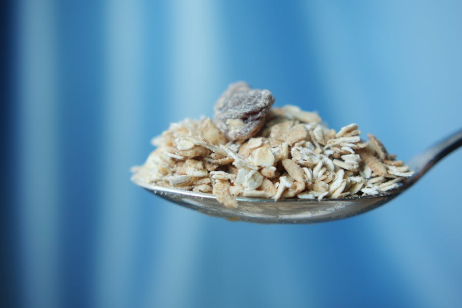 A spoonful of nutritious oats against a blue backdrop, perfect for healthy eating concepts.